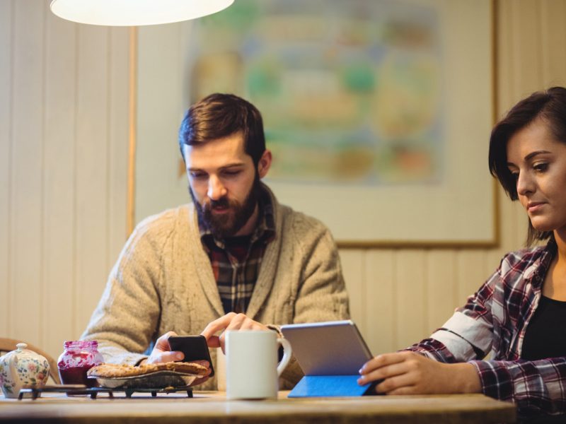 Couple using digital tablet and mobile phone at home